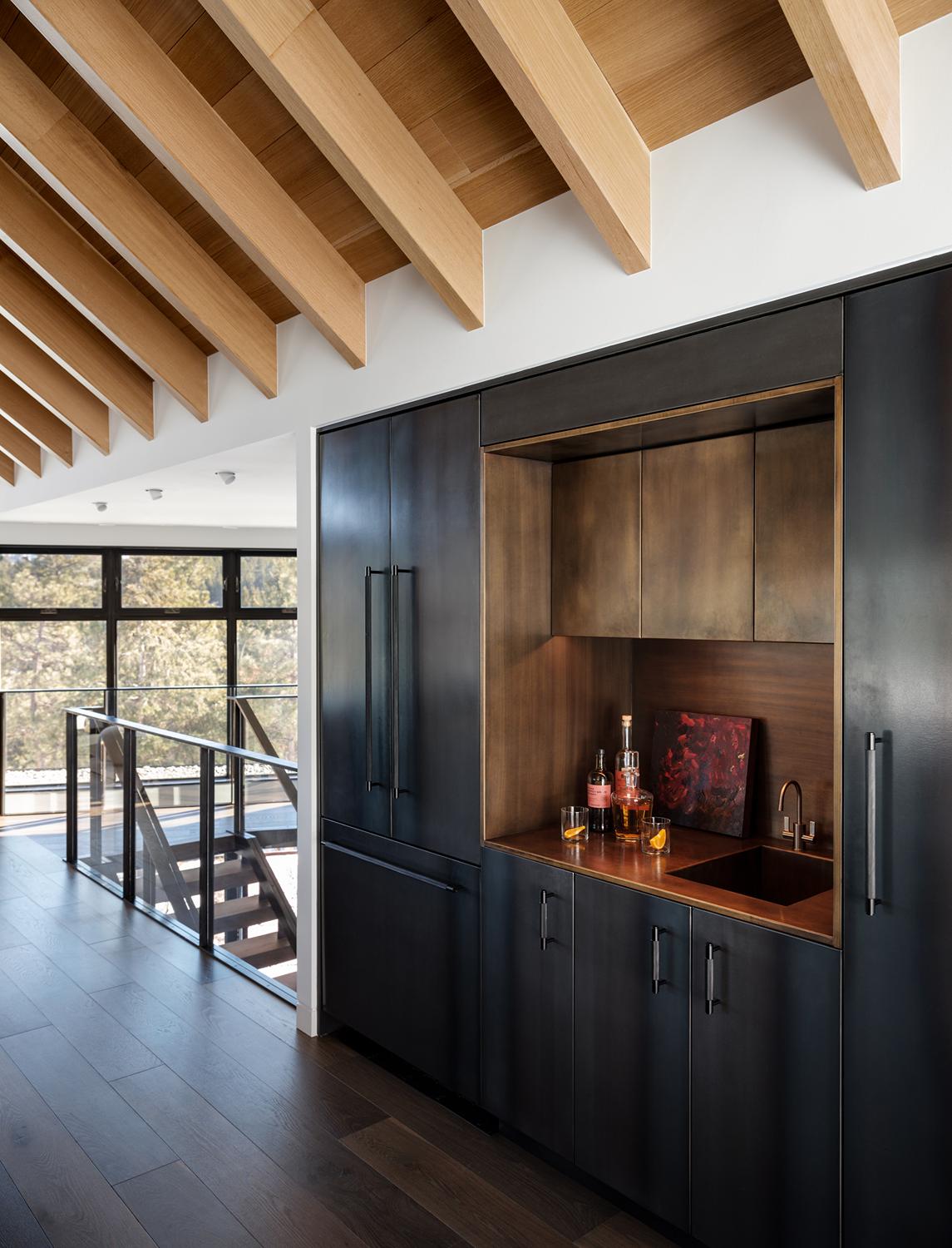 Modern Boulder home bar with black cabinetry, copper accents, and wood beam ceiling overlooking mountain landscape