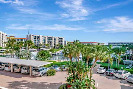 Condominium complex with palm trees, landscaped grounds, and covered parking beneath a blue sky.