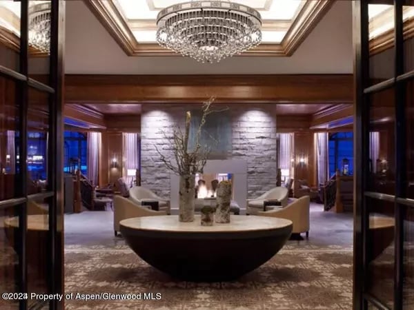 Furnished lounge with a crystal chandelier, stone fireplace, and round display table.