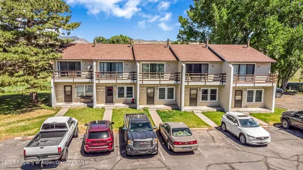 Attached two-story homes with balconies and parked vehicles along the front.
