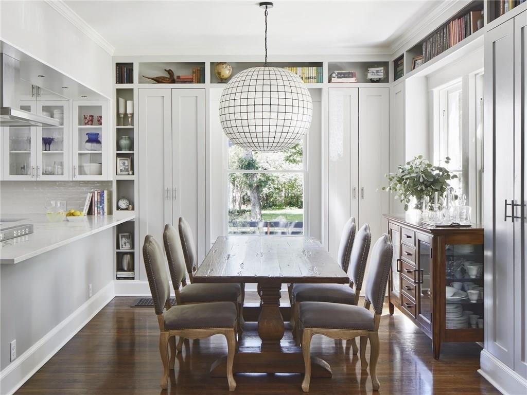 Dining area with built-in bookshelves and cabinetry flanking a large window, beneath a round capiz-shell chandelier, in a Pemberton Heights home on Northwood Road in Austin, Texas. Architectural renovation by McWalters Collaborative.