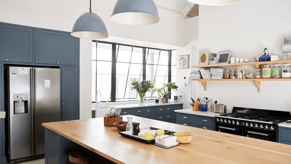 Bright kitchen with dark blue cabinets, a wide butcher-block island, and large windows.