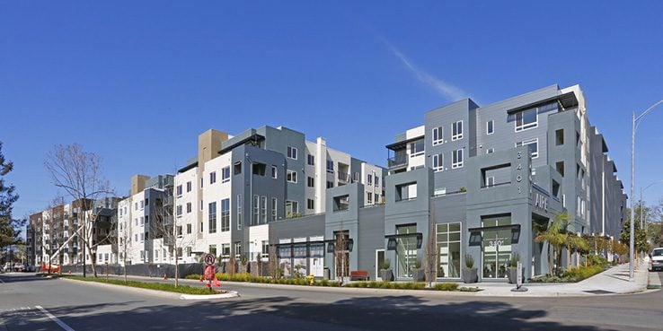 Modern multi-story apartment buildings with storefronts along a North San Jose street.