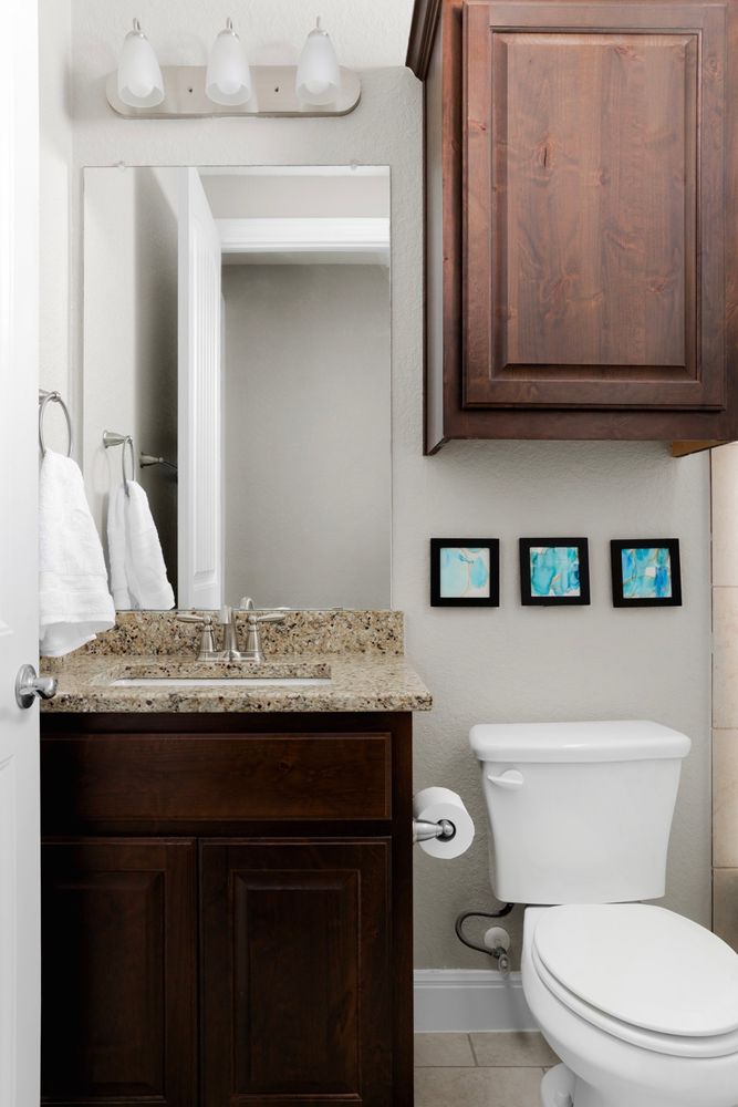 Bathroom with a dark wood vanity, granite countertop, and three blue framed artworks.