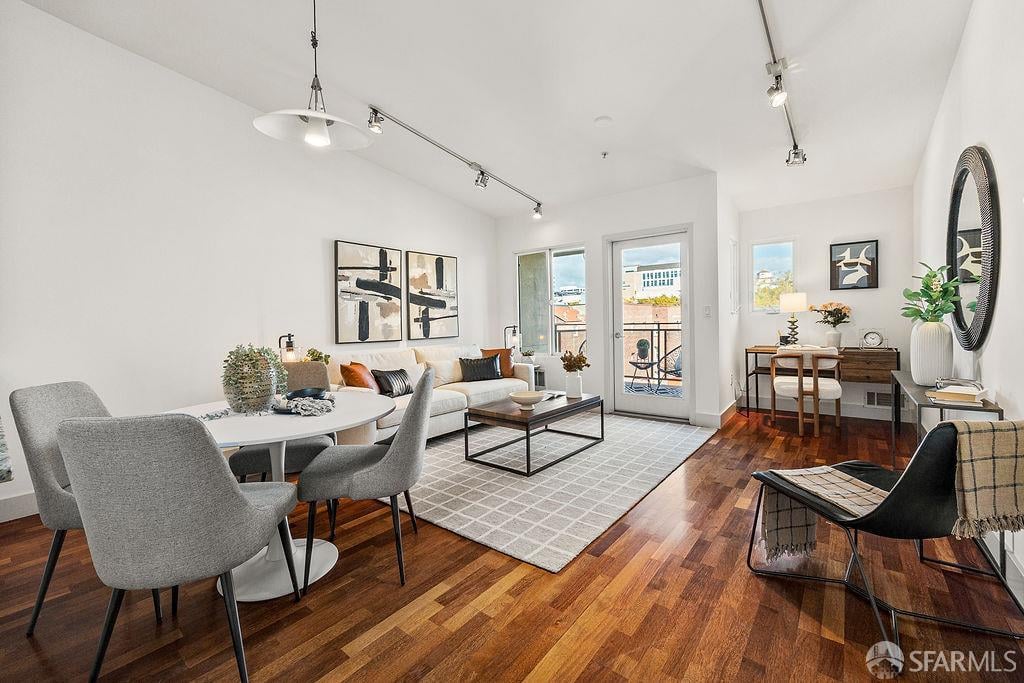 Staged living and dining room with hardwood floors and glass doors opening to a balcony.