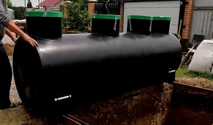 Large black cylindrical barbecue smoker with several top vents in an outdoor yard.