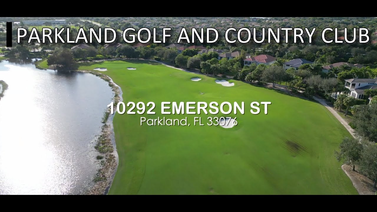 Aerial view of a green golf course beside a lake, with homes along the fairway.