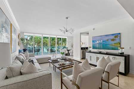 Bright living room with a sectional sofa, armchairs, and sliding glass doors overlooking greenery.