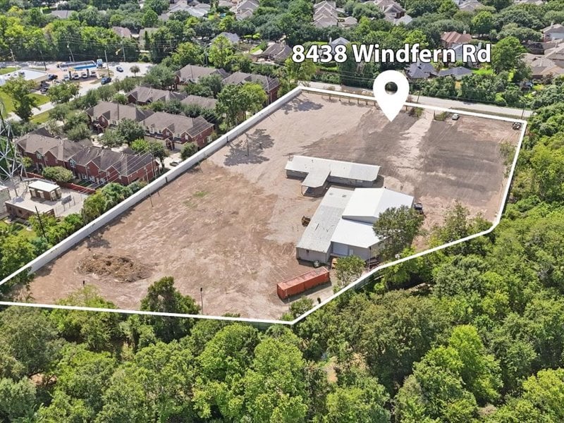 Aerial view of a large cleared parcel outlined in white, with a building and surrounding trees.