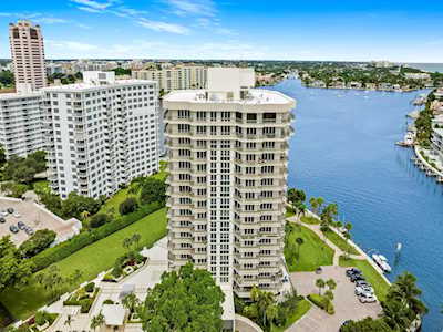 Waterfront condominium towers beside a broad blue waterway, seen from above.