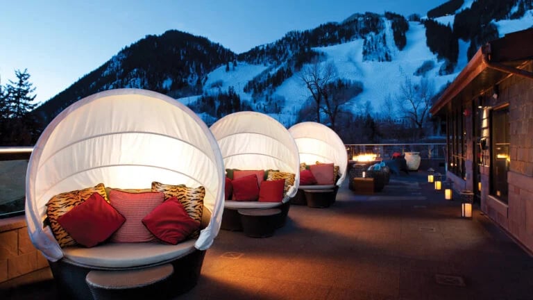 Mountain-view terrace with glowing round daybeds and lanterns at dusk.