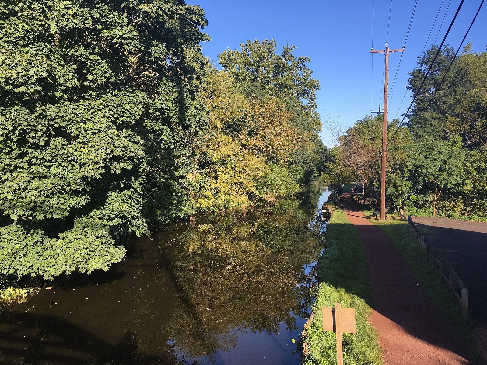 The Delaware Canal and its towpath lined with green trees on a sunny day in Yardley, PA