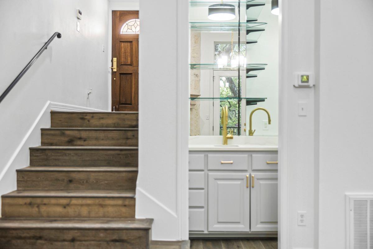 Entry staircase beside a glass-shelved wet bar, Barton Hollow, Westlake, Austin.