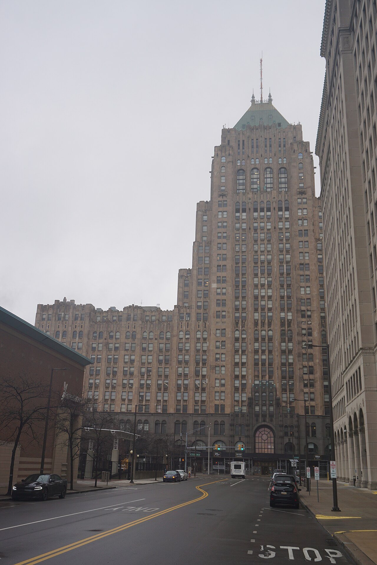 The David Stott Building’s tall tan tower and green pyramidal roof above a downtown Detroit street.