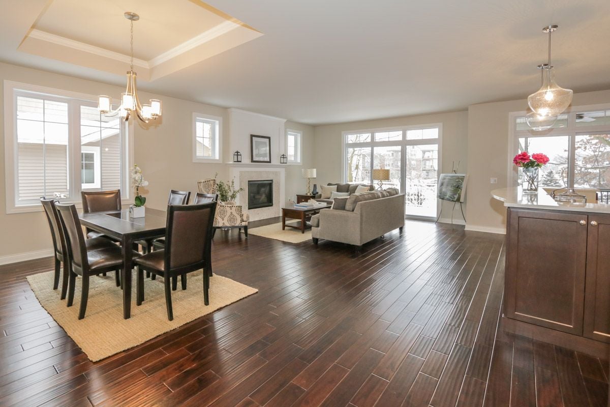 Open-plan dining and living area with dark hardwood floors, a fireplace, and large windows.