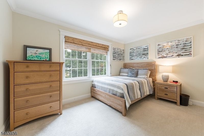 Bedroom with a wide window, gray-striped bedding, and light wood furniture.