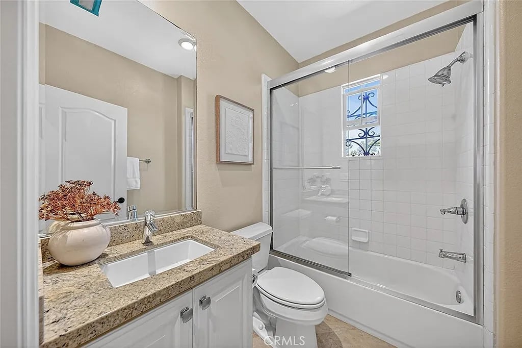 Bathroom with granite vanity and glass-enclosed tub and shower.