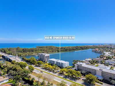 Aerial view of waterfront buildings along Spanish River Boulevard, with the Atlantic Ocean beyond.