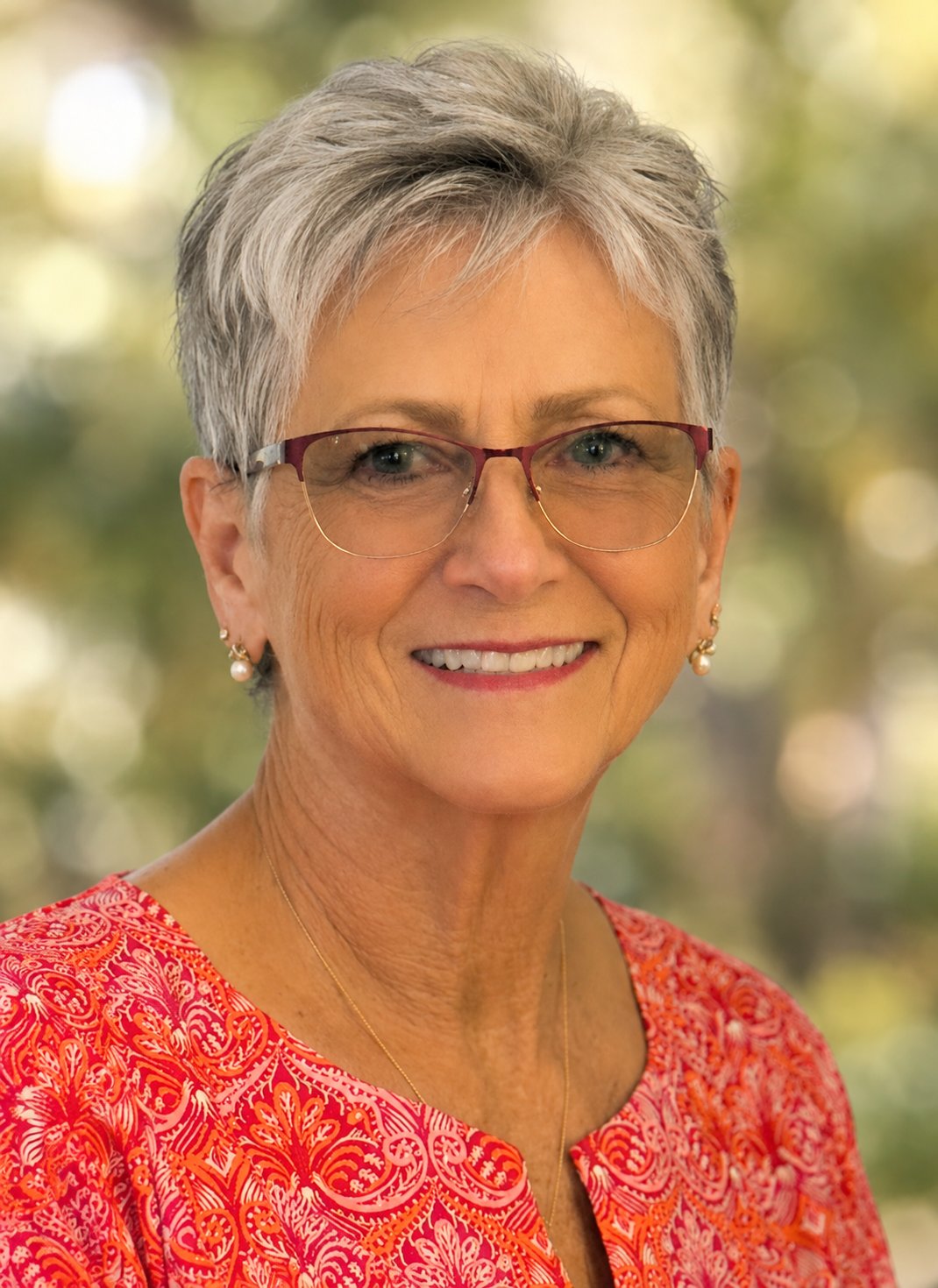 Peggy Wark smiling in glasses and a red patterned top.