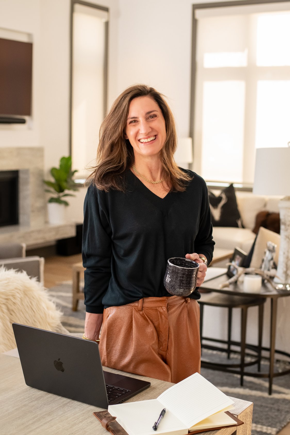 Samantha Gerstein smiling with a mug beside a laptop and open notebook.