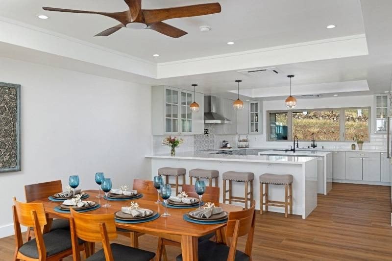 Open-plan kitchen and dining area with a large island, white cabinetry, and a set wooden dining table.