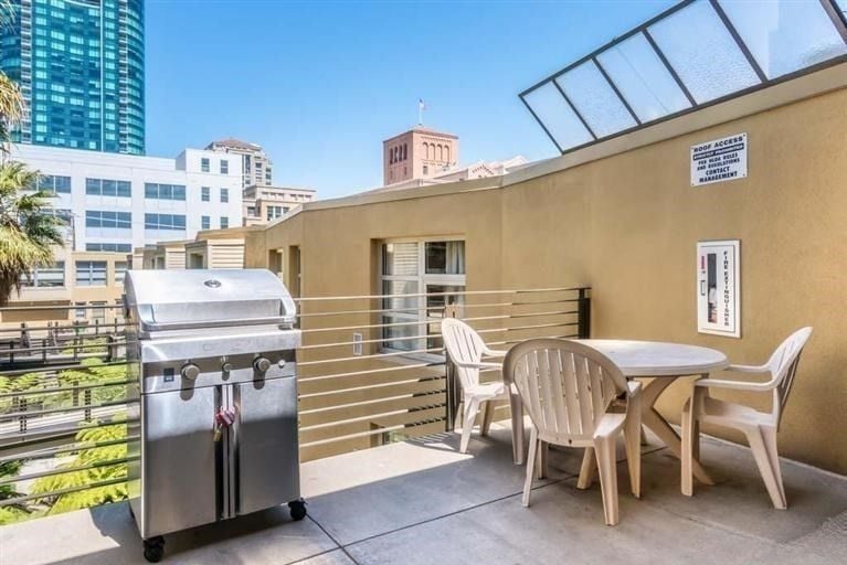 A rooftop patio at 400 Spear Street, with a stainless steel grill and a white plastic table and chairs, offering views of the surrounding city buildings.