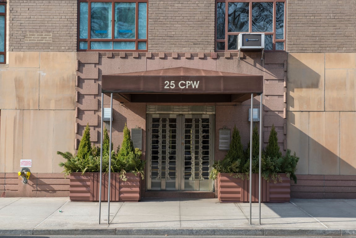 Entrance to 25 Central Park West, with a “25 CPW” canopy and evergreen planters.