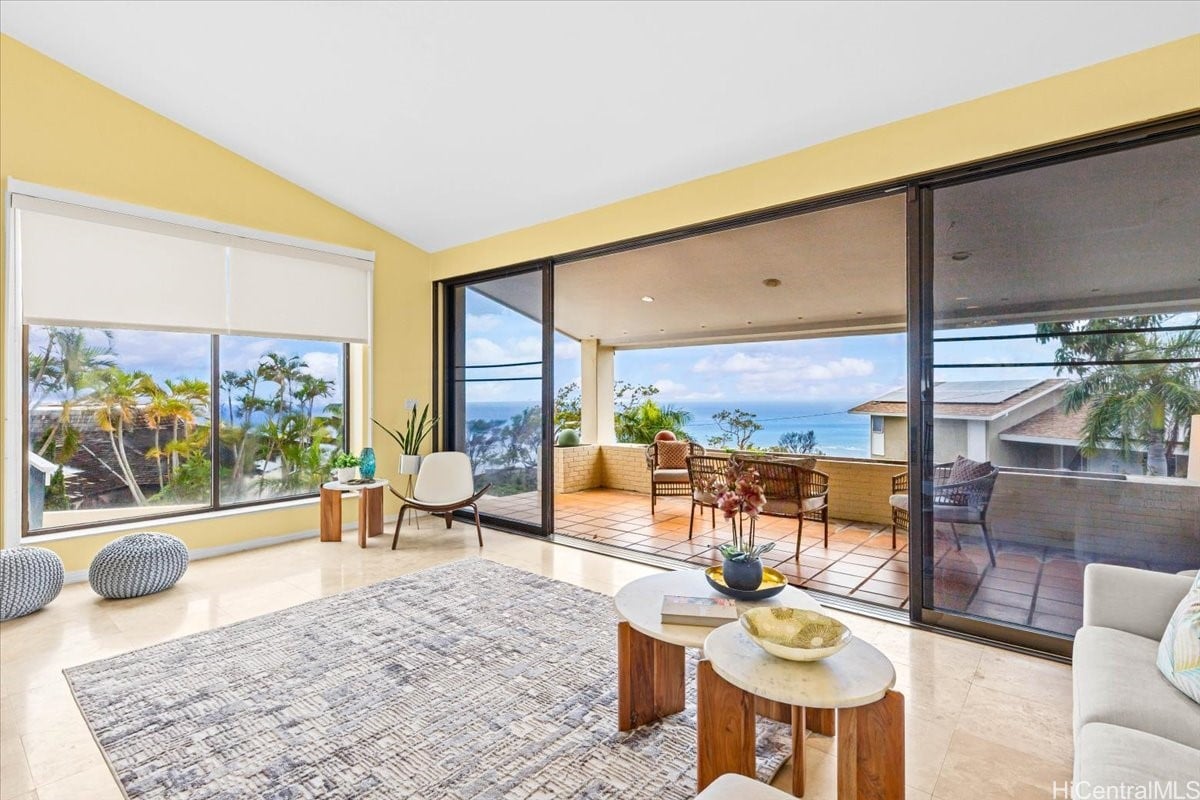Living room with yellow walls, sliding glass doors, and a lanai overlooking the ocean.
