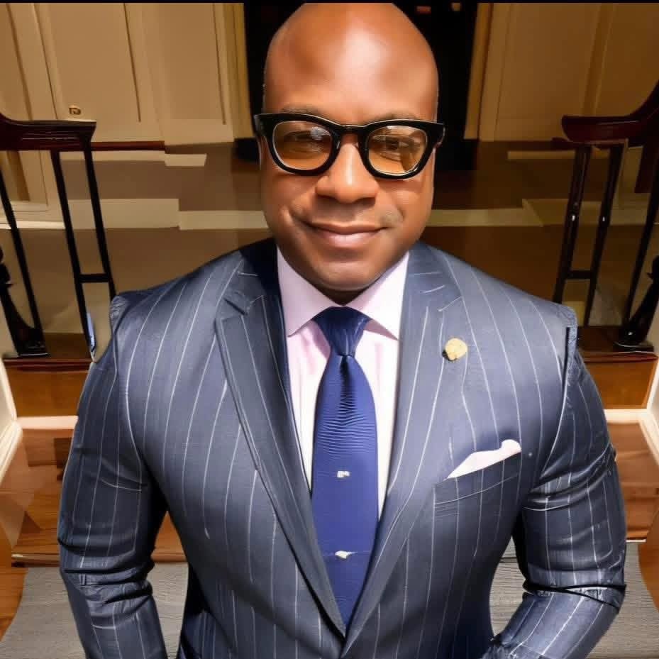 David Peterson wearing black glasses and a navy pinstripe suit with a blue tie.