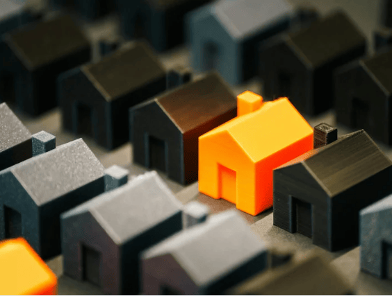 Bright orange model house among rows of dark miniature homes.