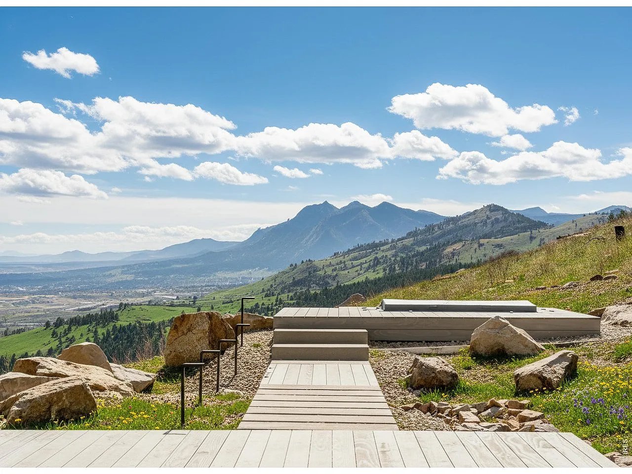 Mountain vista from a deck with a wooden walkway and stone landscaping.
