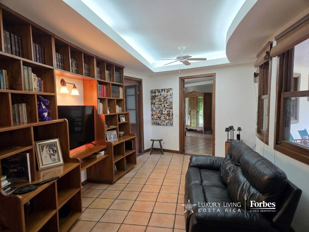 Living room with built-in wooden bookshelves, a television, and a black leather sofa.
