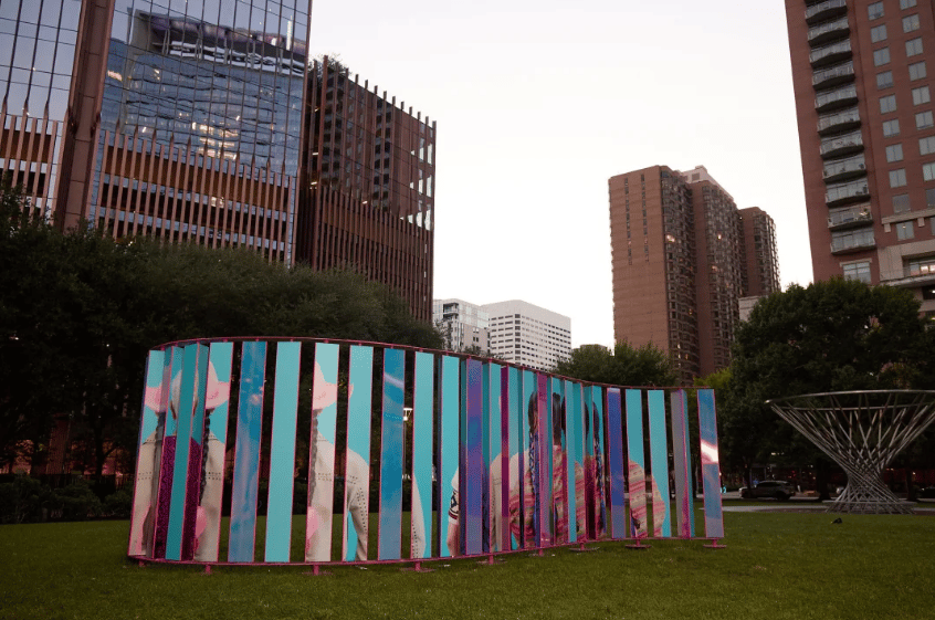 Colorful public art panels on the lawn at Discovery Green, with Houston high-rises behind them.