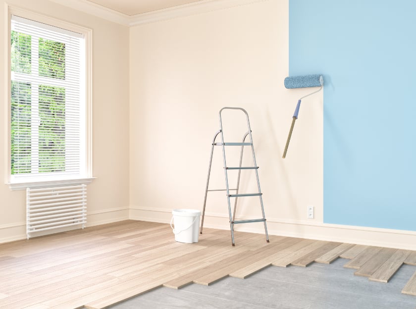 Interior home improvement project featuring wall painting and new flooring installation in a bright room
