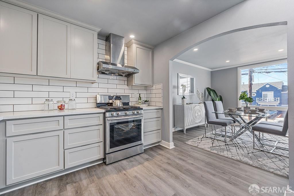 Kitchen with white cabinets and stainless steel appliances opening into a furnished dining area.
