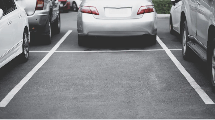 Empty parking space between parked cars in a lot.