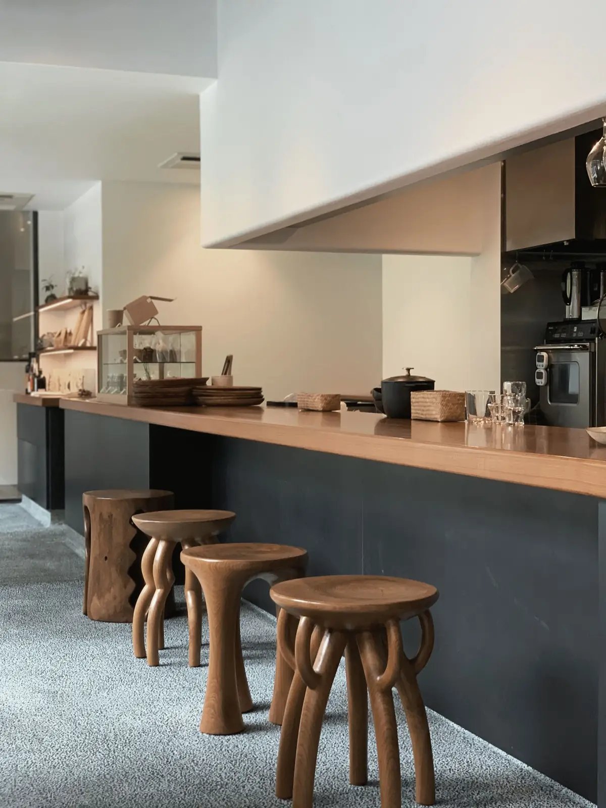 Long wooden counter with carved wooden stools in a bright modern kitchen