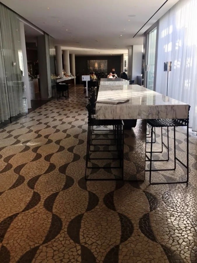 Dining area with a long marble communal table and distinctive patterned floor.