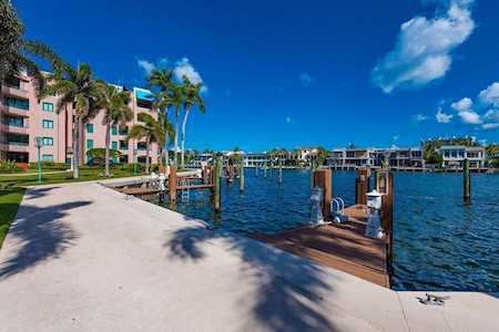 Waterfront condominium buildings beside a marina dock and paved shoreline.