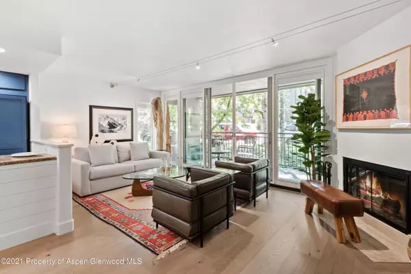 Living room with leather armchairs, a fireplace, and glass doors opening onto a balcony.