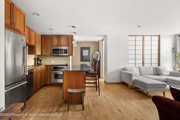Open kitchen and living area with wood cabinetry, stainless appliances, and a central island.