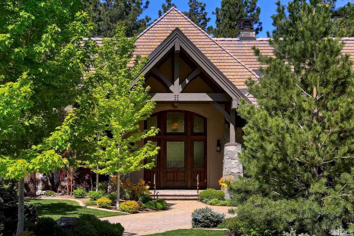 Home with a timber-framed gabled entrance, shingle roof, and landscaped front walkway.
