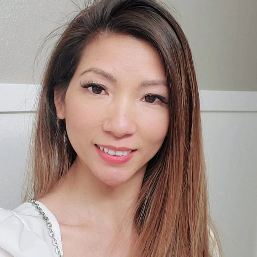 Nikki-Nu Nguyen smiling, with long brown hair and a white top.