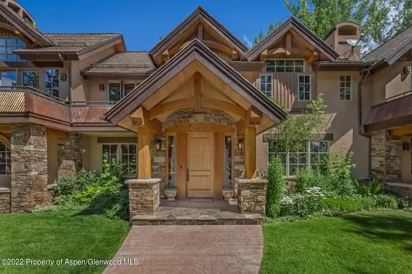 Large home with timber gables, stone accents, and a landscaped front lawn.