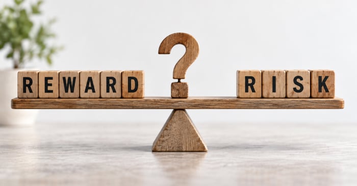 Wooden balance scale weighs “REWARD” against “RISK,” with a question mark at its center.