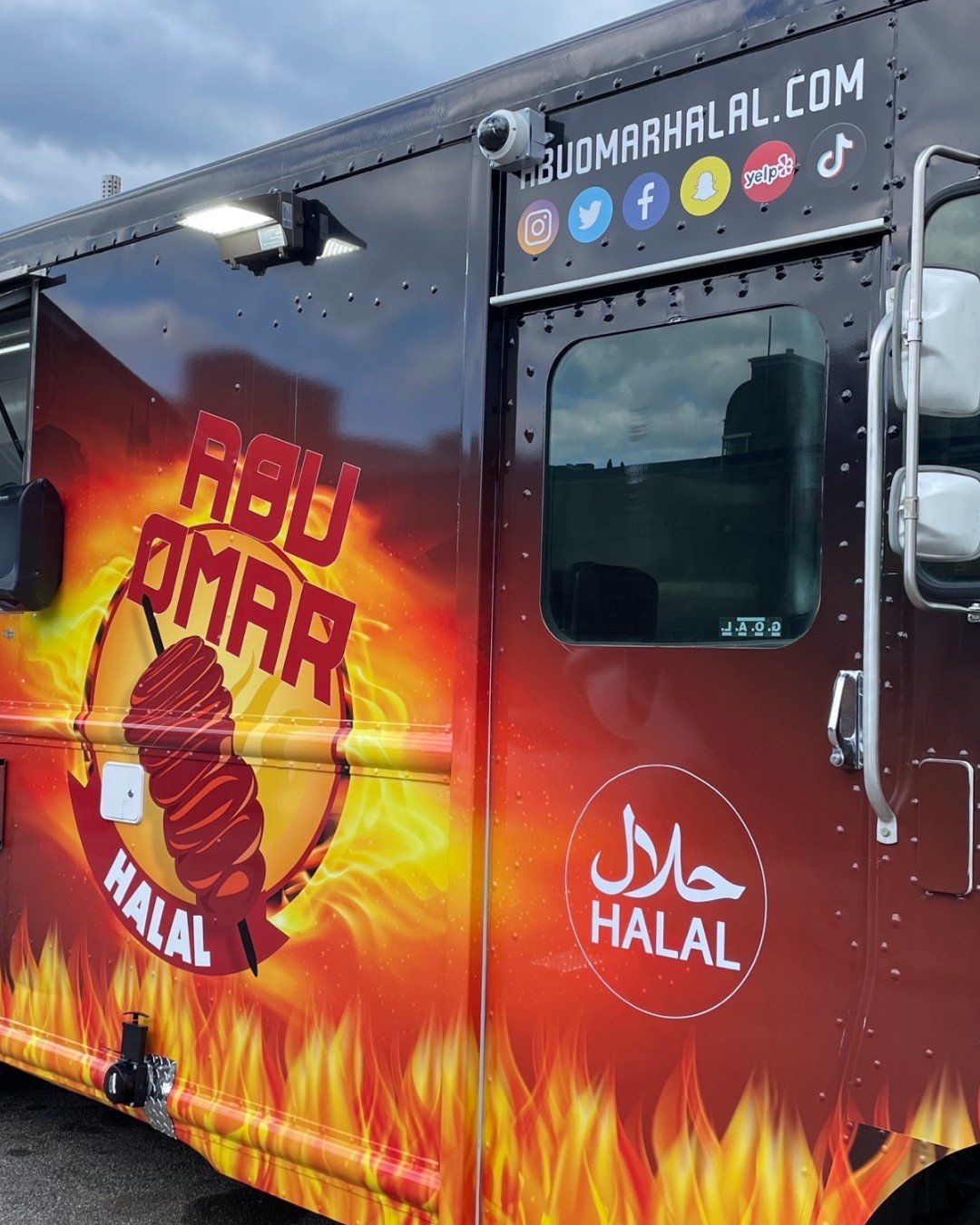Red Abu Omar halal food truck with flame graphics and a kebab illustration.