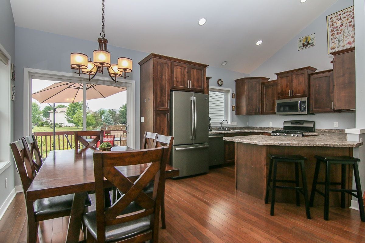 Kitchen and dining area with dark wood cabinets, a granite island, and sliding doors to a deck.