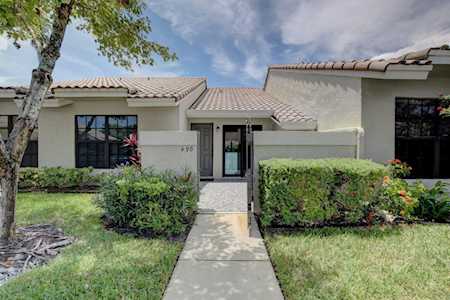Single-story stucco home with a central entrance, tiled roof, and landscaped front lawn.
