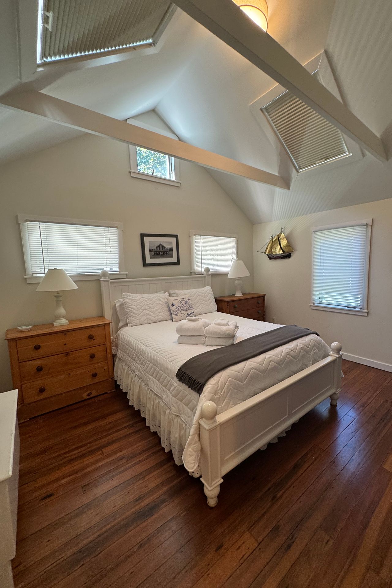Bedroom with a white four-poster bed beneath a vaulted ceiling with exposed beams.