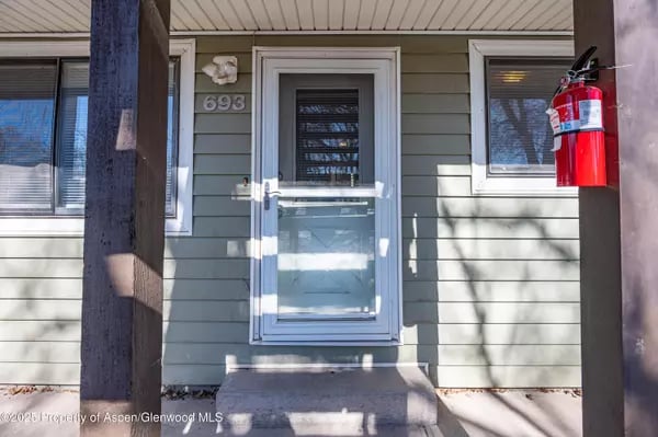 Home entrance with a blue-green door, white-trimmed windows, and a red fire extinguisher.